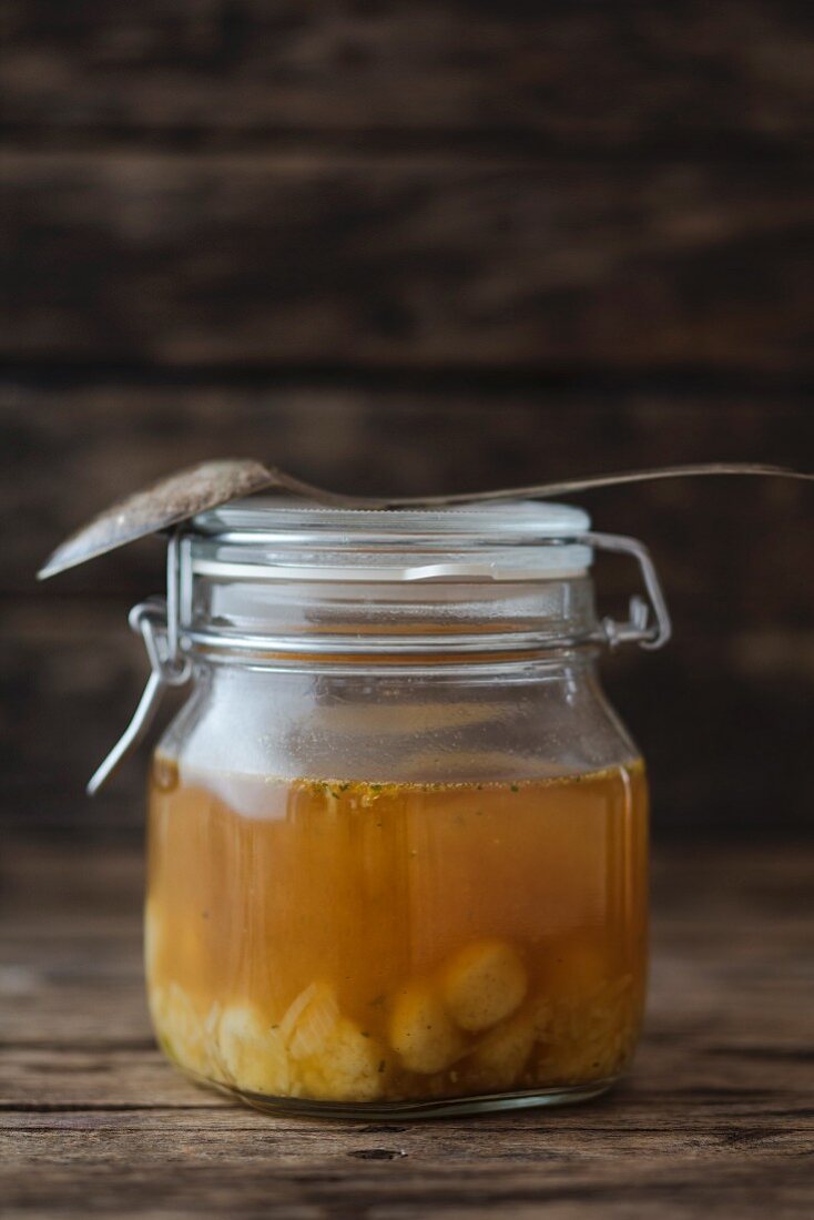 Clear broth with bone marrow dumplings in a glass jar