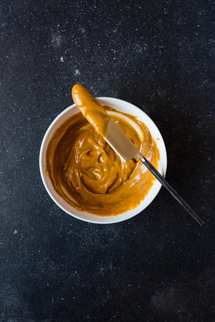 Caramel sauce in a small bowl with a knife