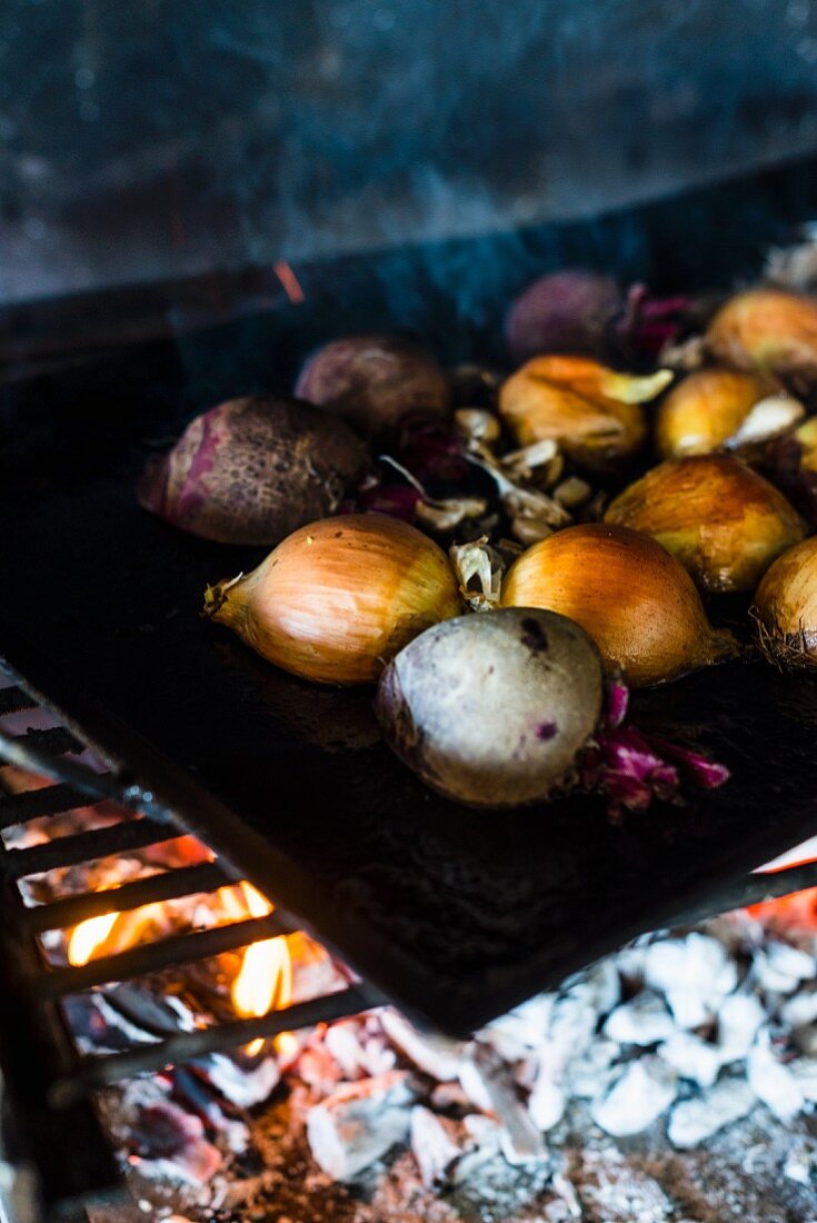 Root vegetables and onions on a charcoal grill