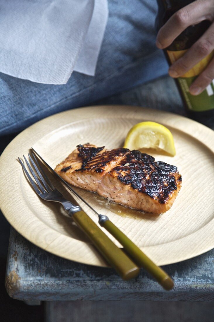 Salmon on a bamboo plate with boy holding a beer bottle