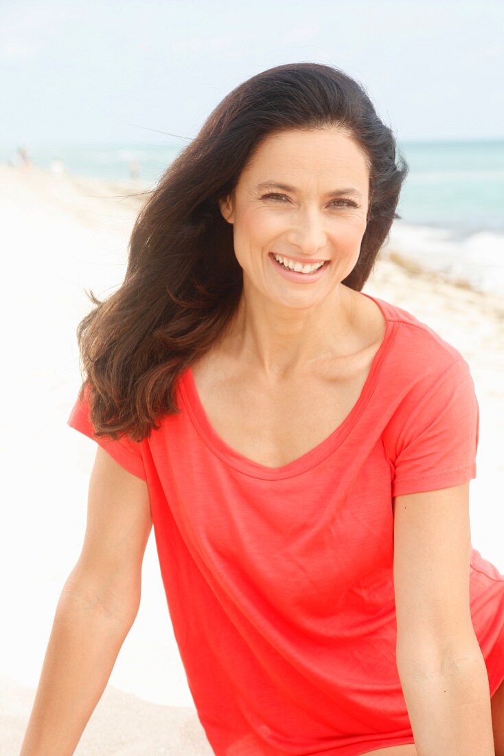 Brünette Frau in rotem T-Shirt am Strand