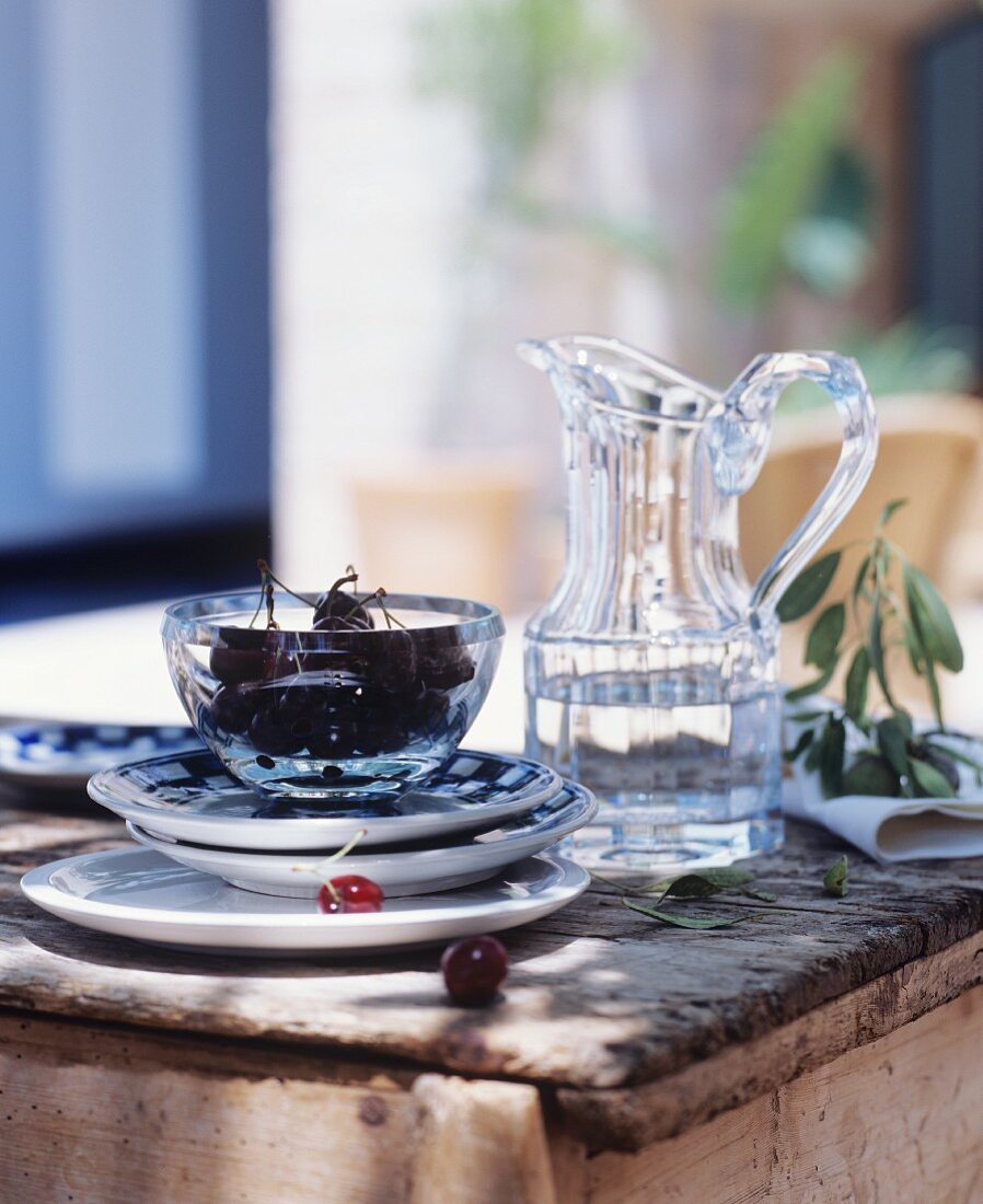 Water jug and bowl of cherries on rustic wooden table