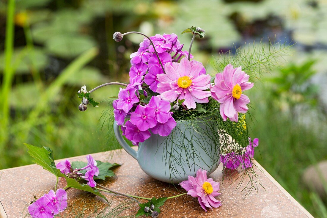Posy of Japanese anemones and fennel leaves on table in garden
