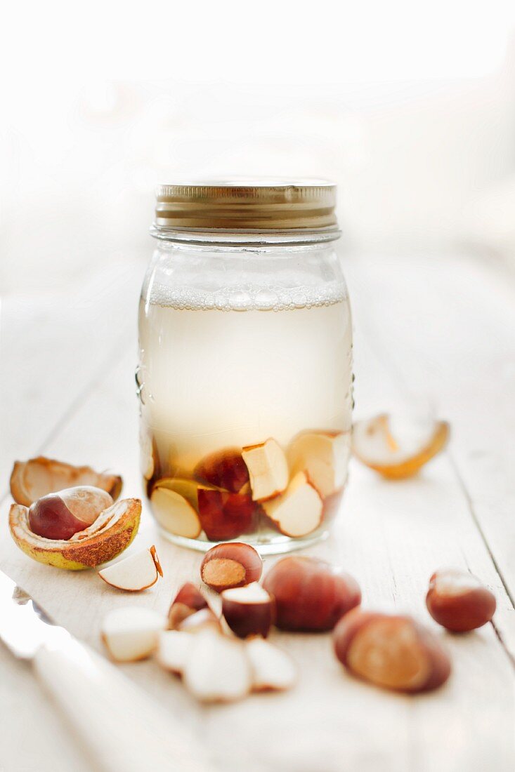 Frothy water and freshly cut chestnuts in a screw top glass jar
