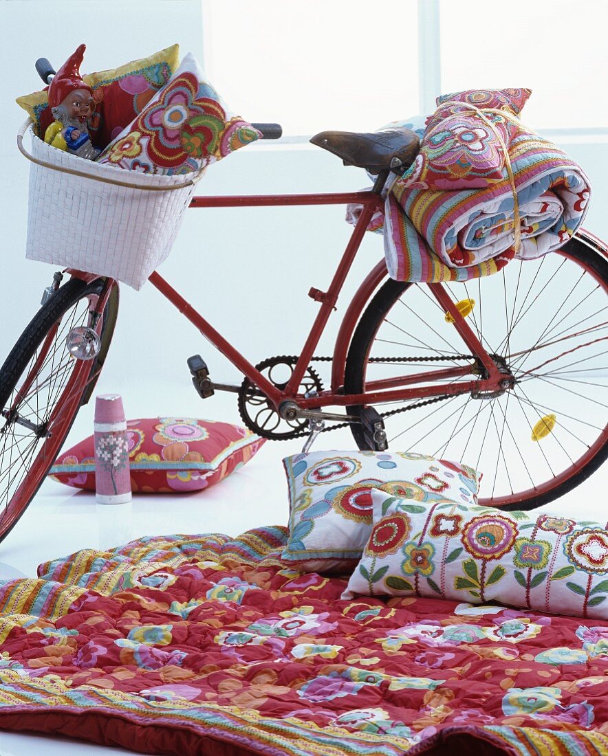 Red bicycle and floral textiles arranged for indoor picnic