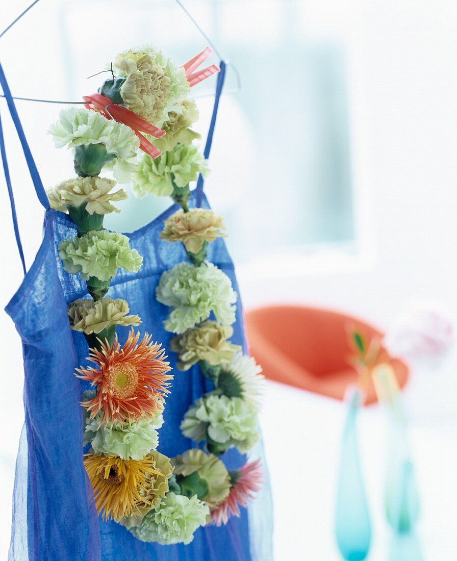 Zur Kette aufgefädelte Blumen an einem blauen Kleid