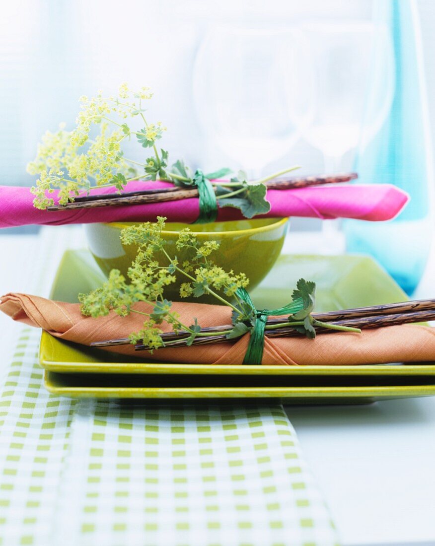 Napkin and chopsticks tied with posy of lady's mantle on green plates