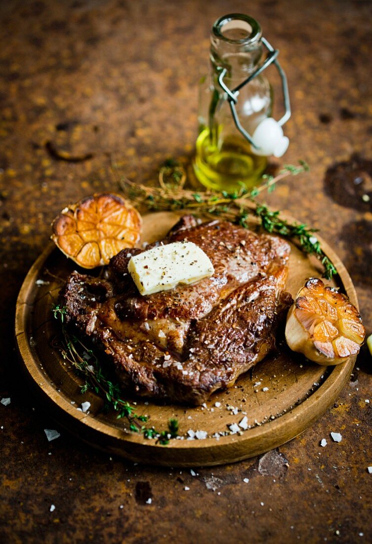 A steak with garlic and butter on a wooden board