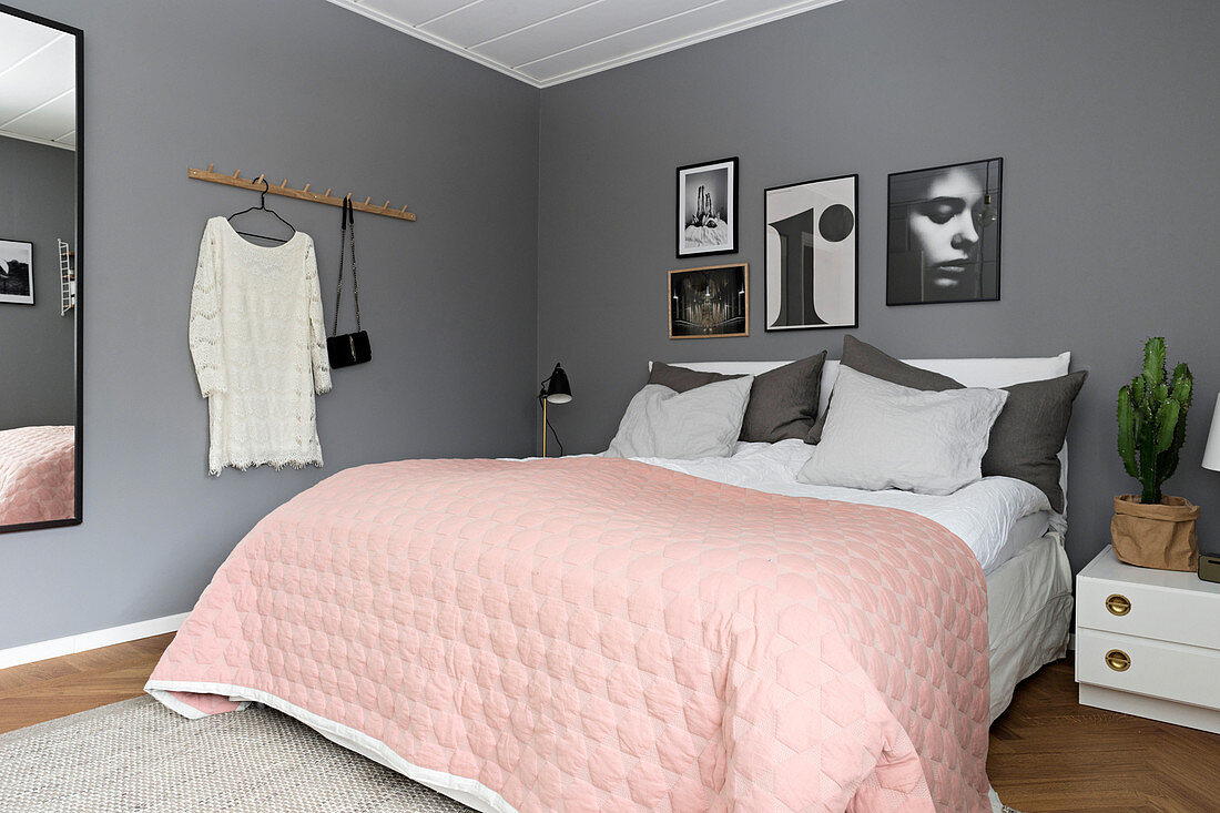 Rosa Tagesdecke über dem Bett im Schlafzimmer mit grauen Wänden