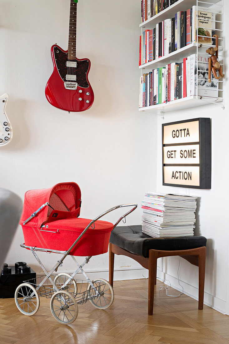 Vintage-style red pram in front of illuminated panel