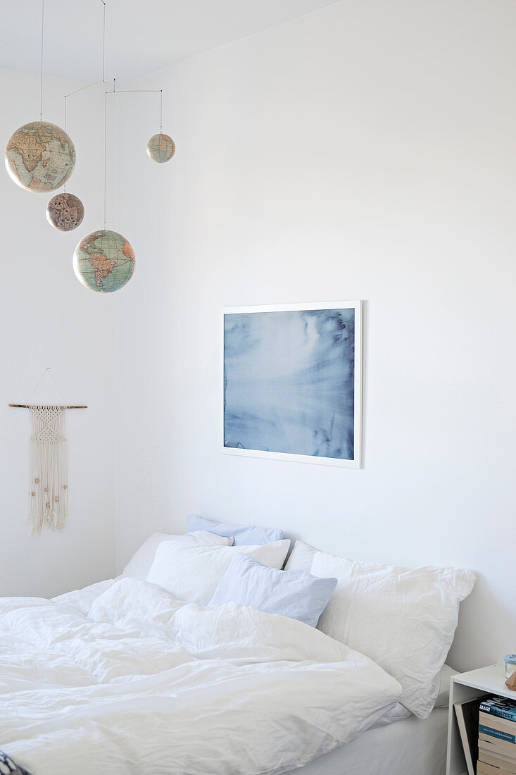Mobile made from globes above bed in white bedroom