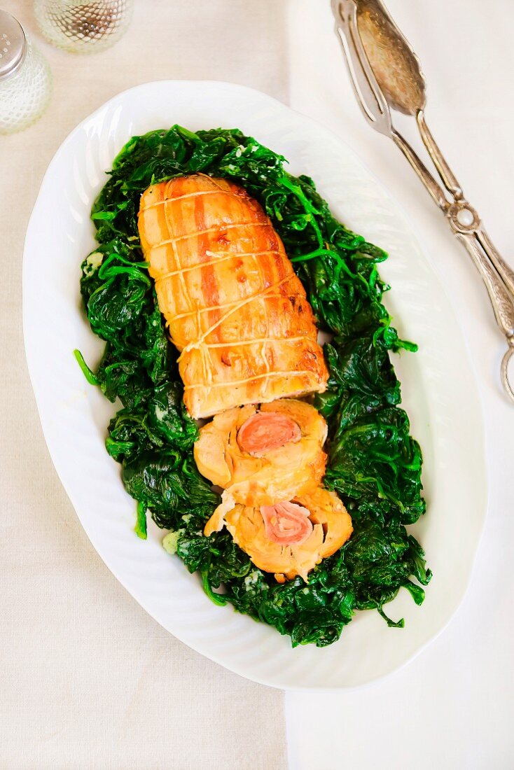 Chicken roulade with ham and spices on sautéed spinach