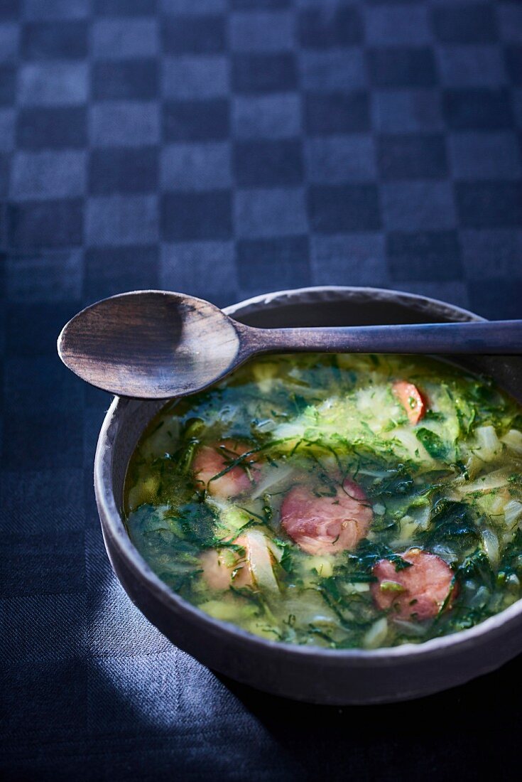 Herb soup with slices of sausage