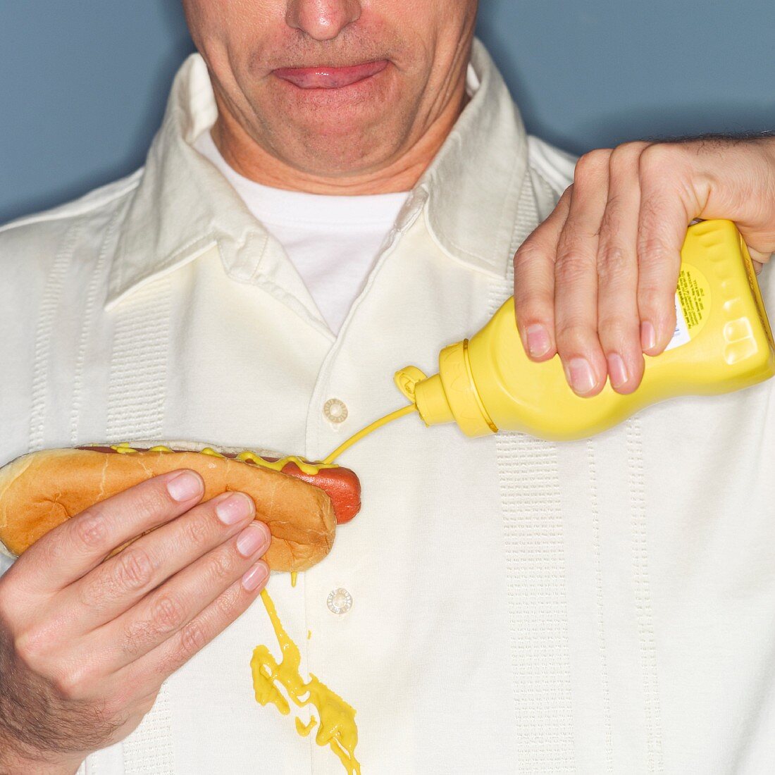 Mann hält Hot Dog in der Hand und bekleckert sich mit Senf