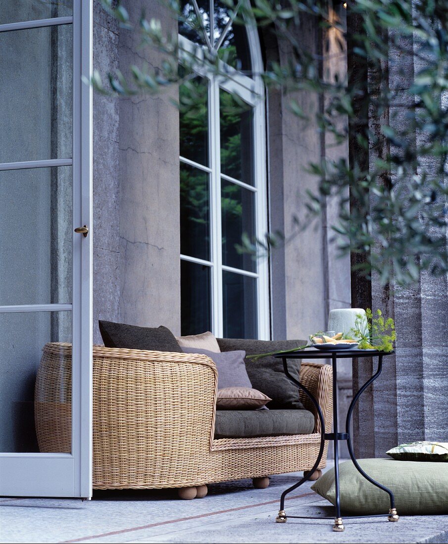 Oval rattan sofa and metal table outside Classical house