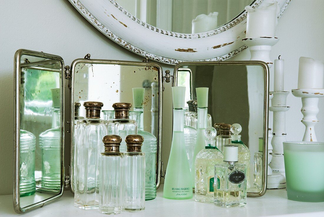 Collection of vintage-style perfume bottles in front of mirror