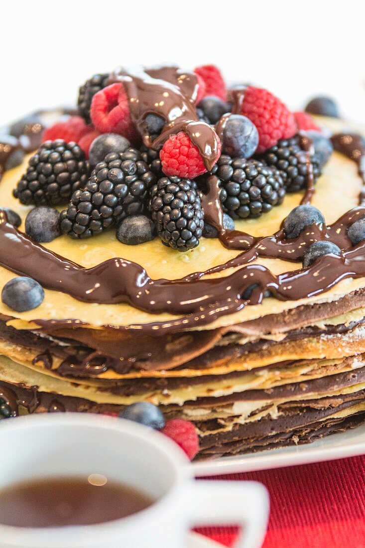 A pancake cake with berries and chocolate sauce