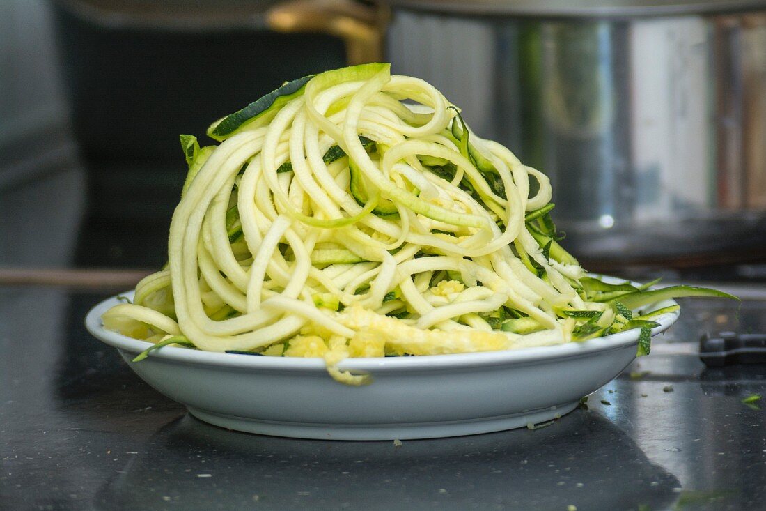 Zoodles (spiralized zucchini noodles) on a plate in the kitchen