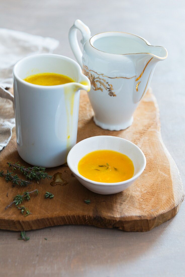 Orange sauce in a jug on a wooden board