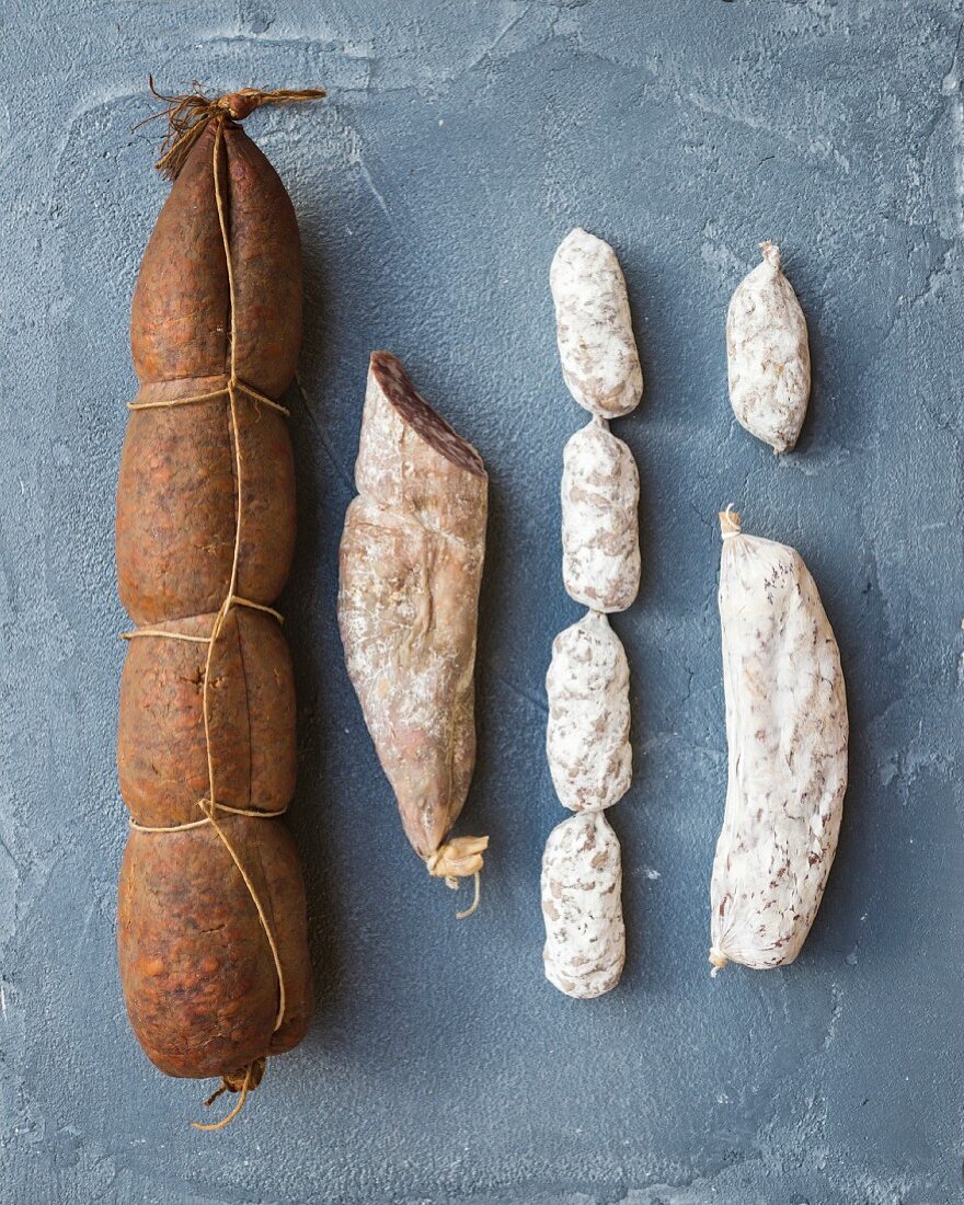 Italian salami sausages of different kinds over a rough grey-blue concrete background, top view