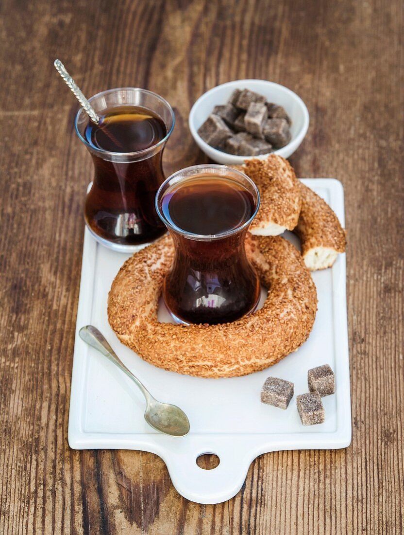 Turkish traditional black tea in a glass and turkish bagel simit on white ceramic serving board