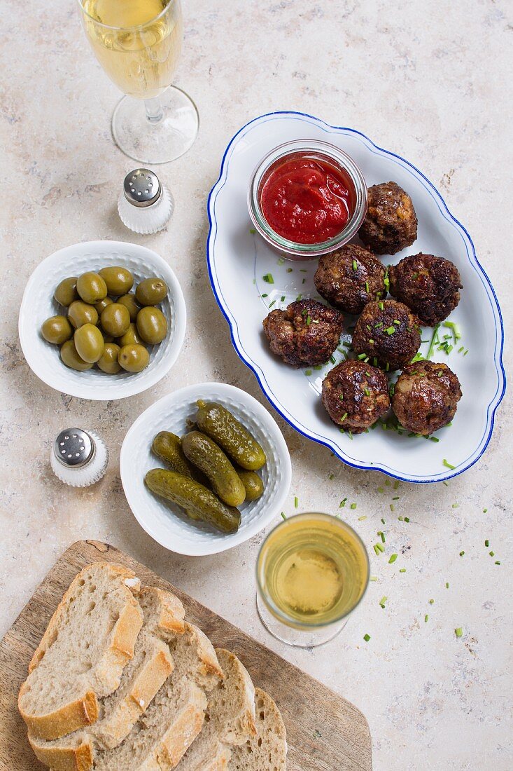 Meatballs with ketchup, olives and cornichons
