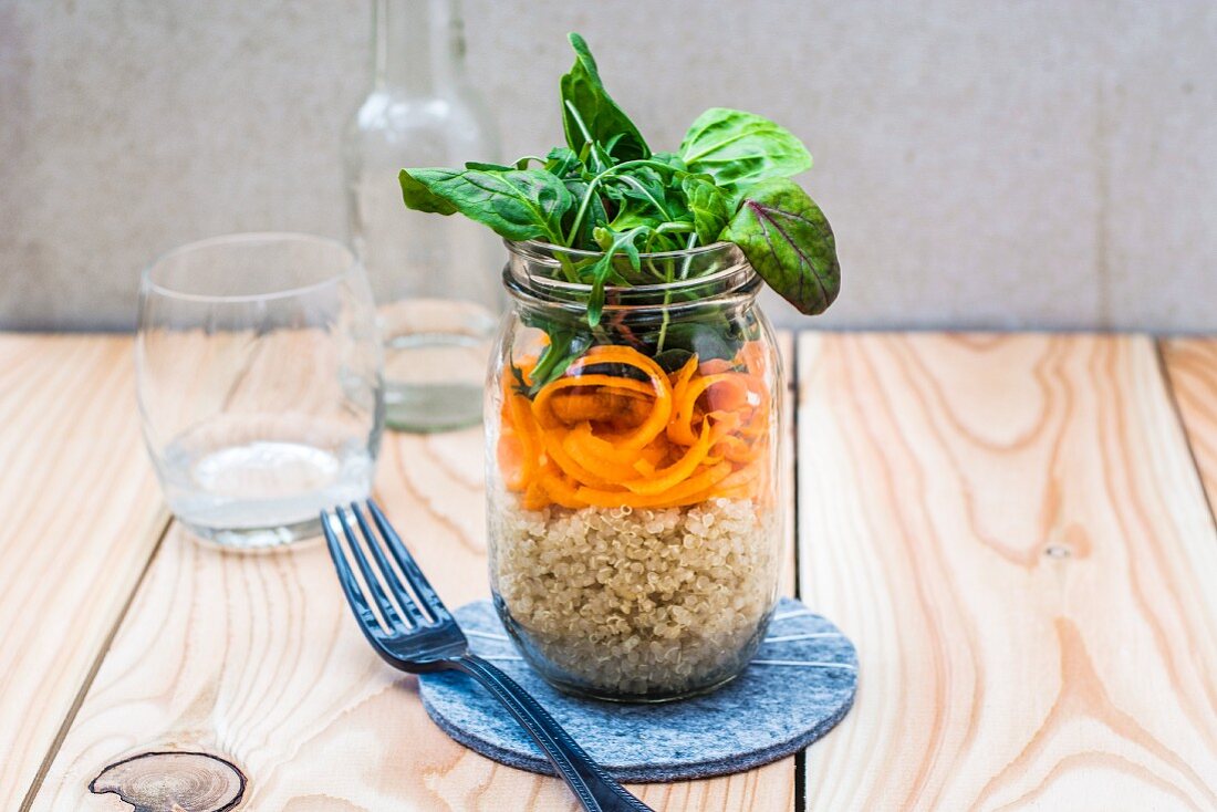 A layered quinoa and carrot salad in a glass