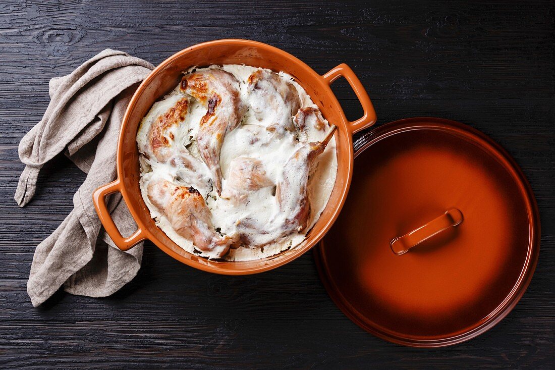 Rabbit in sour cream on dark wooden background