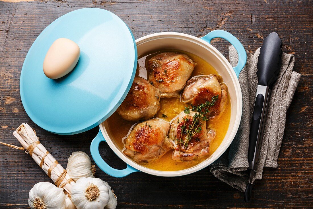 Roast chicken stew in cast iron pan on wooden background