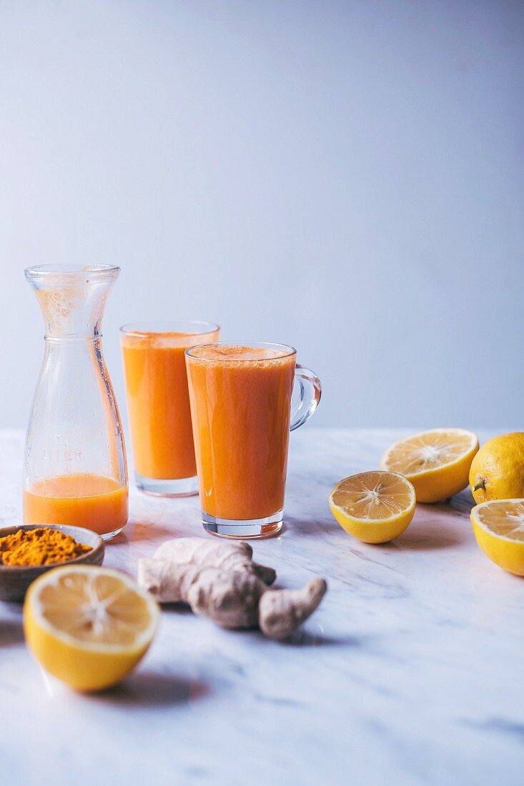 Glasses of orange, lemon and carrot juice with turmeric and ginger