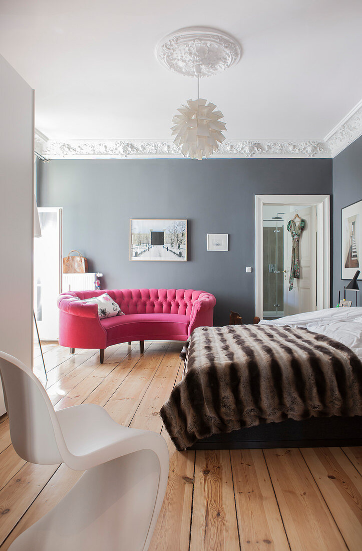 Curved pink sofa in bedroom with grey walls