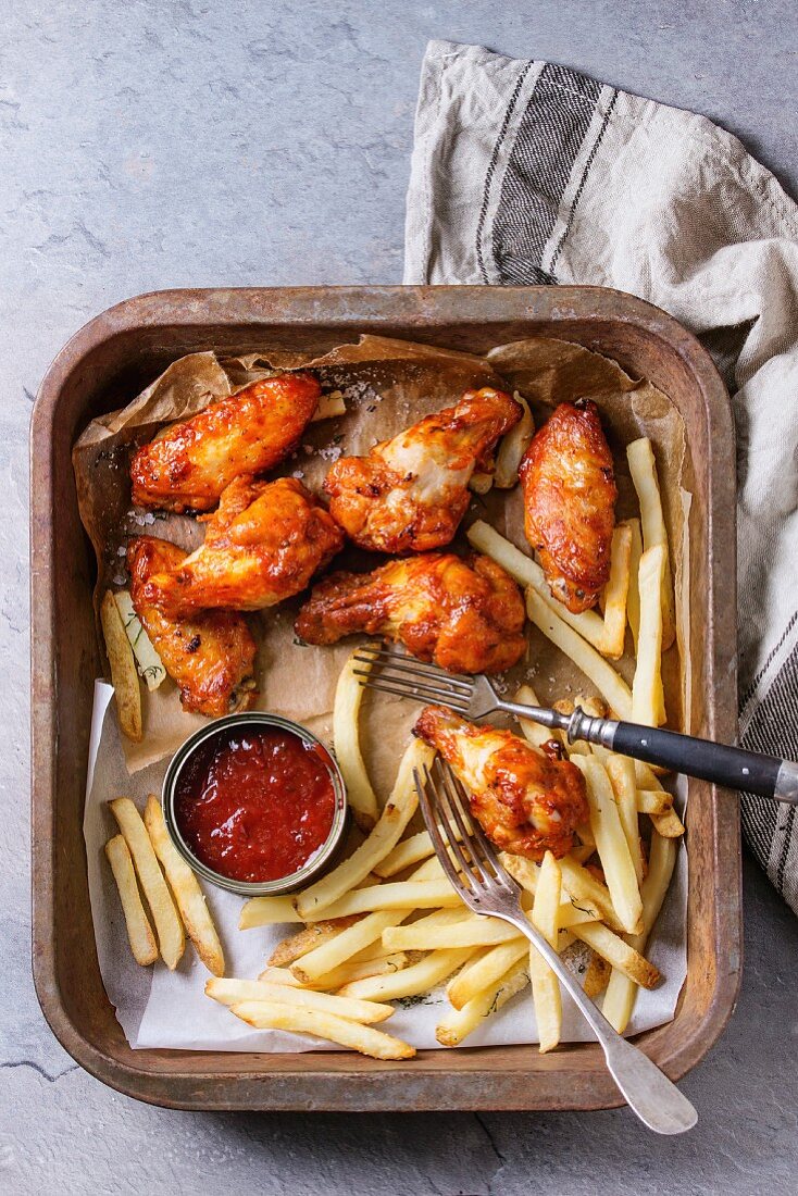 Fast food fried spicy chicken legs, wings and french fries potatoes with salt and ketchup