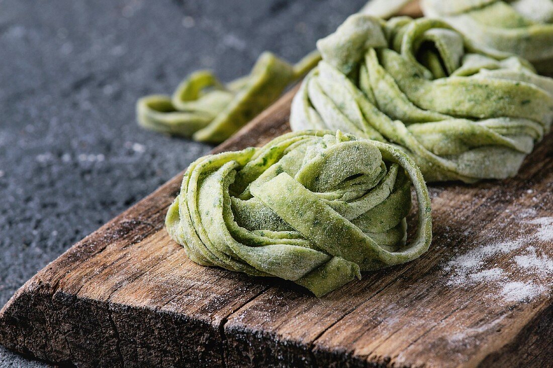 Fresh raw uncooked homemade twisted green spinach pasta tagliatelle with flour