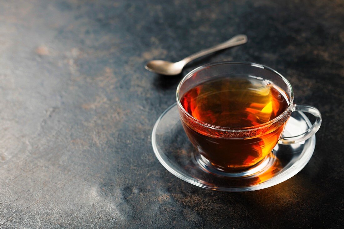 Cup with black tea on rustic metal background