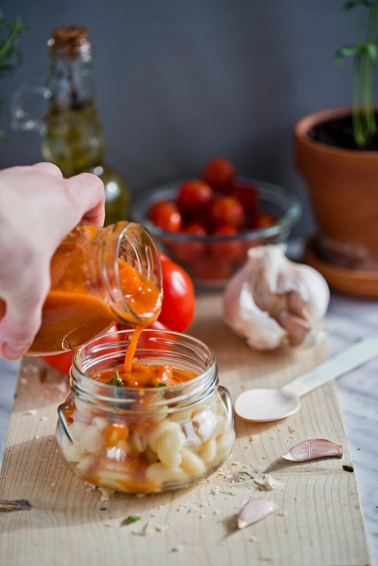 Tomatensugo über Nudeln im Glas gießen
