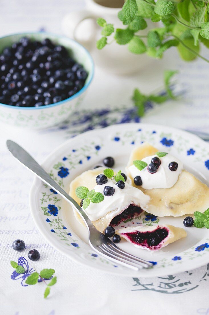 Traditional Polish dumplings (pierogi) with blueberries and sour cream