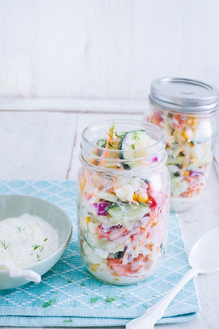 Cauliflower and cucumber salad with yoghurt and dill dressing in glass jars