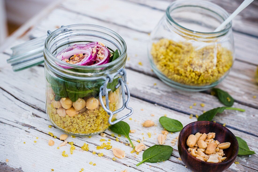 Quinoa curry with baby leaf spinach, chickpeas and red onion in a glass jar