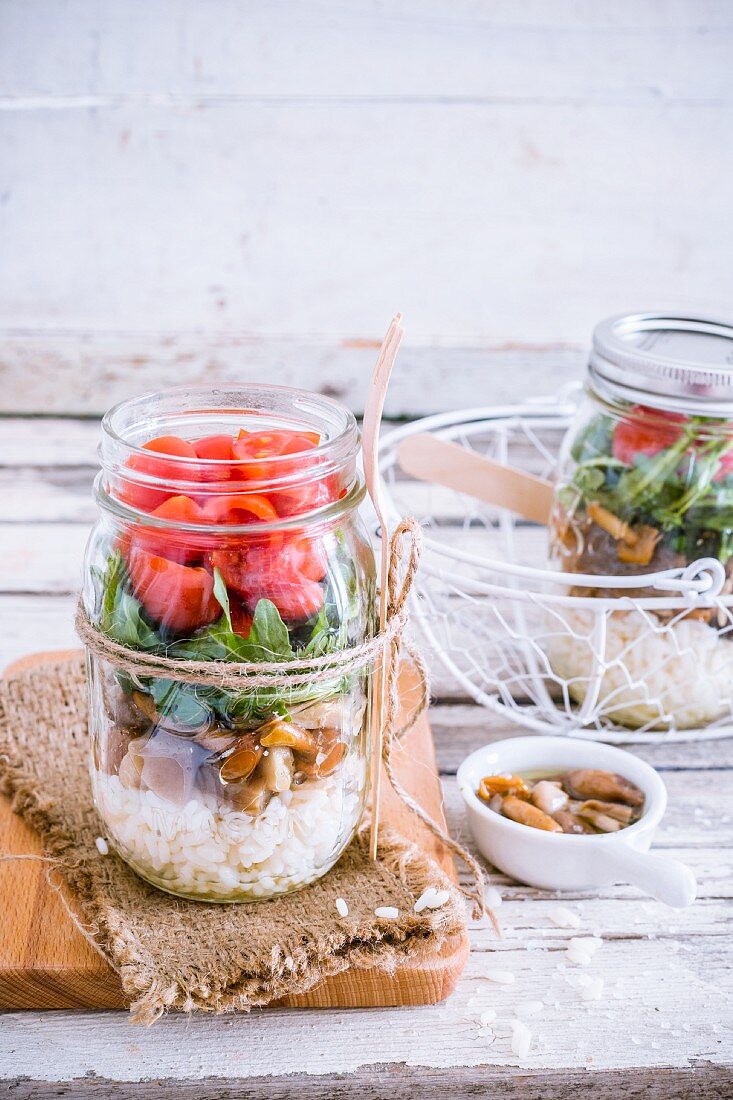 Rice salad with mushrooms, rocket and tomatoes in a glass jar