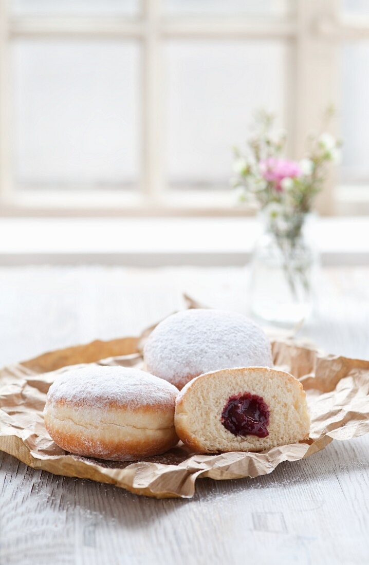 Jam doughnuts on a paper bag next to a window