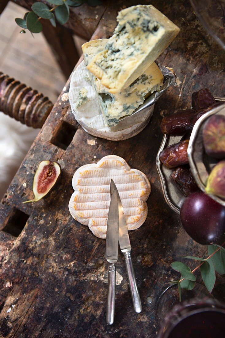Käse, Feigen und Datteln auf altem Holztisch