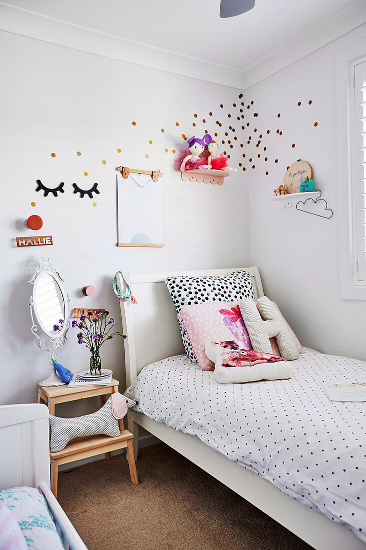Weisses Bett mit gepunkteter Bettwäsche, daneben Nachttisch mit Hundefigur im Kinderzimmer