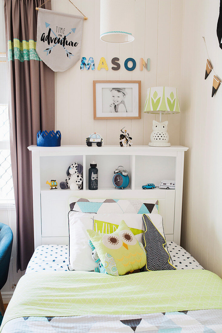 Bed with pillows and a shelf on the headboard in the boy's room