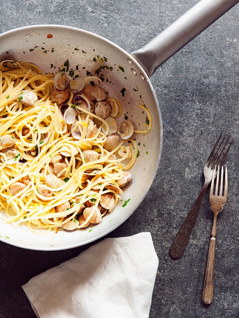 Spaghetti mit Muscheln, Petersilie und Knoblauch in Pfanne (Italien)