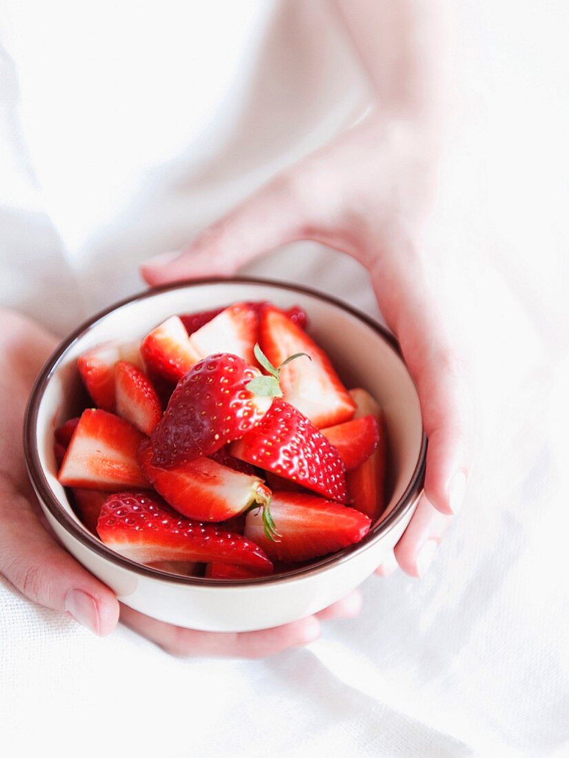 Frauenhände halten Schale mit frischen Erdbeeren