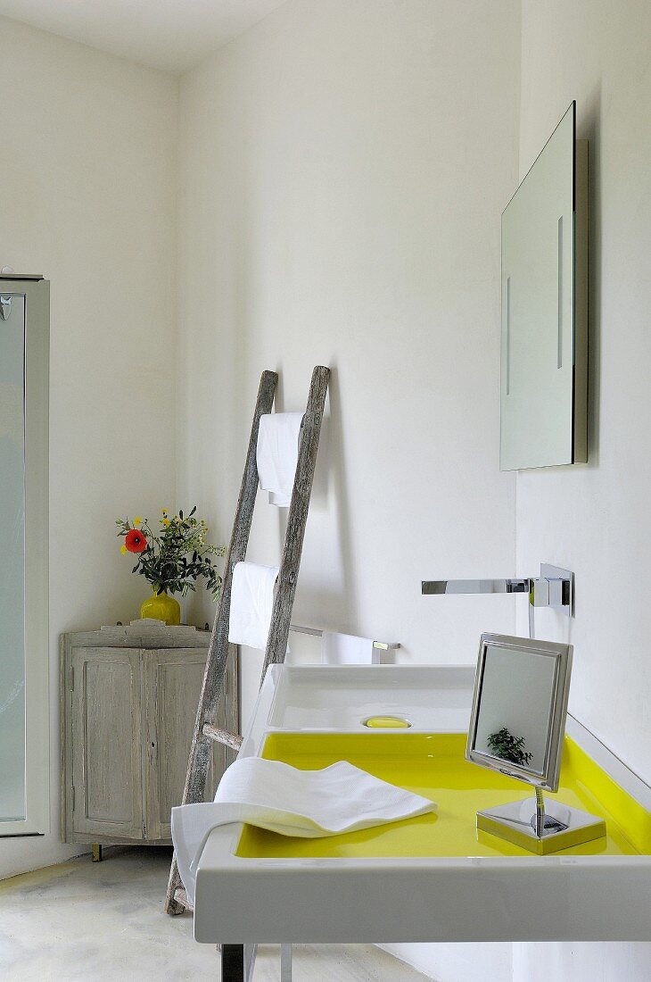 Sink next to vintage ladder and vase of flowers on top of corner cabinet