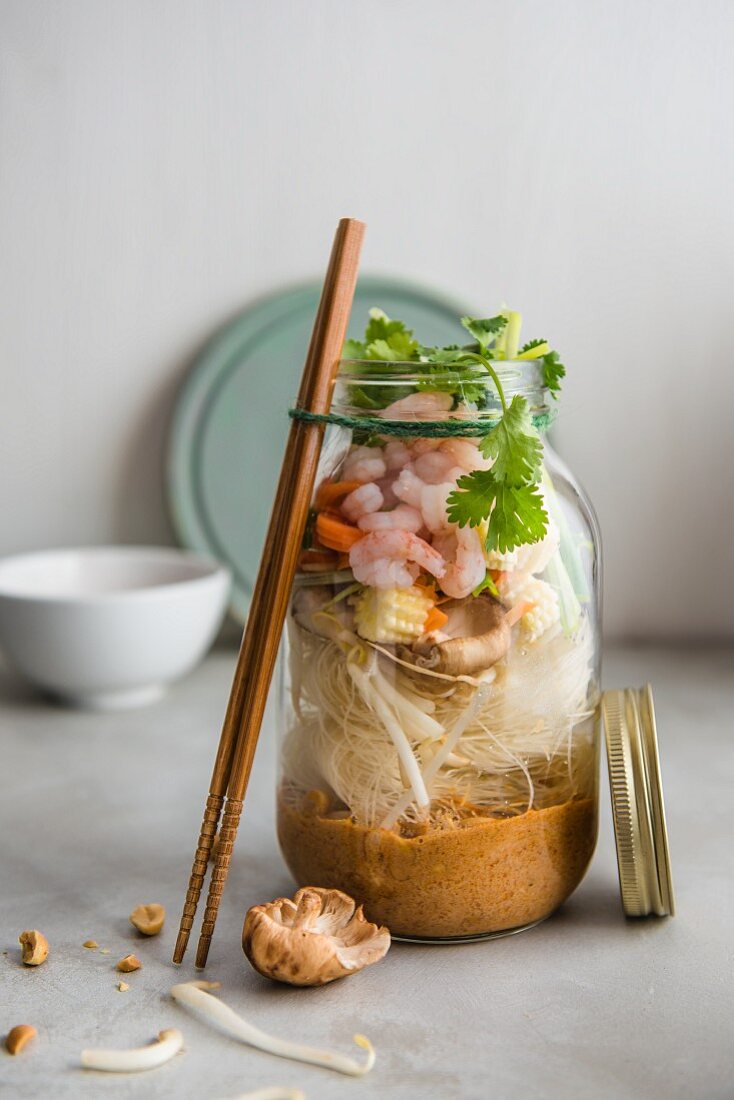 Spicy curried noodle soup with peanuts, vegetables and prawns, garnished with coriander