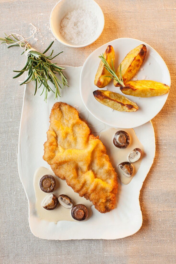 Schnitzel in white wine and mushroom sauce with potato wedges