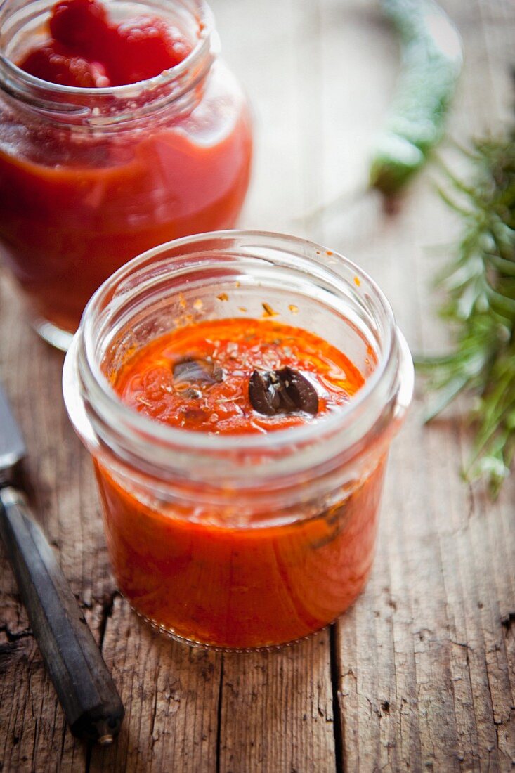 Eingelegte Tomaten und schwarze Oliven im Glas (Italien)