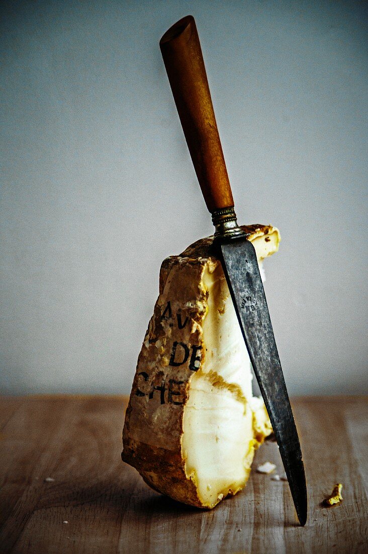 Ein Stück unpasteurisierter Ziegenkäse mit altem Messer